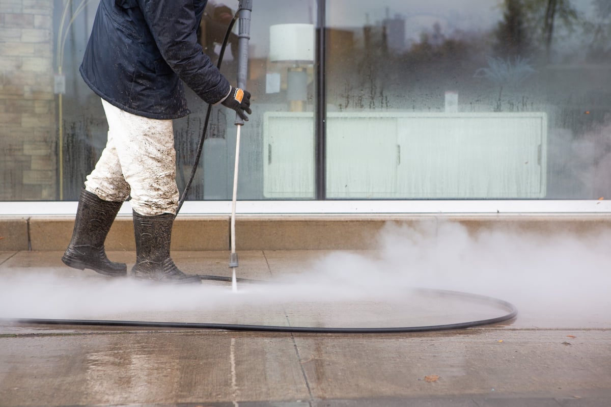 Professional power washing service - worker cleaning sidewalk